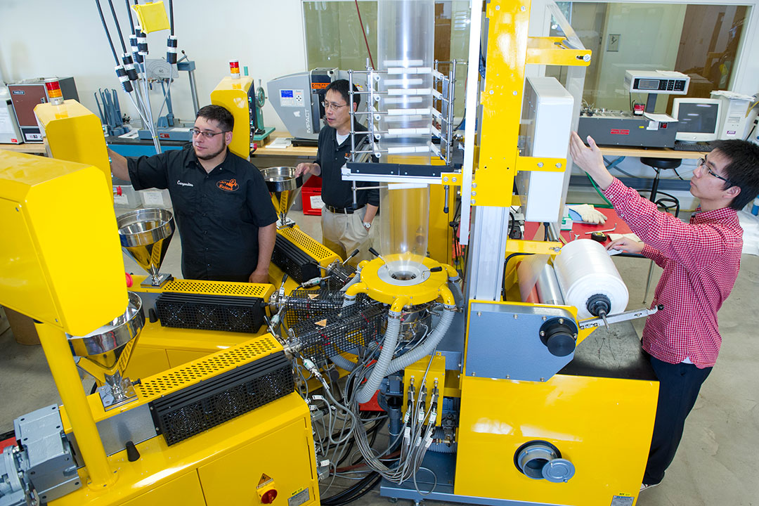 Students work with large, yellow machinery.