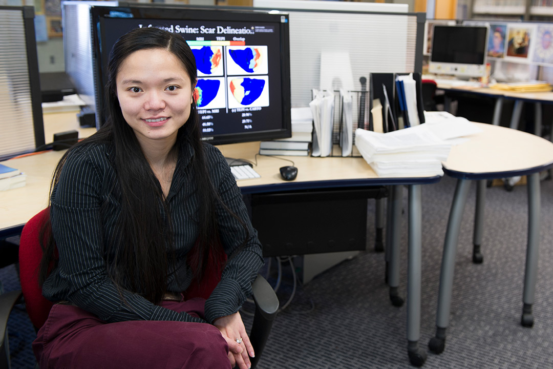 Woman wearing black blouse sits in front of desk with computer.