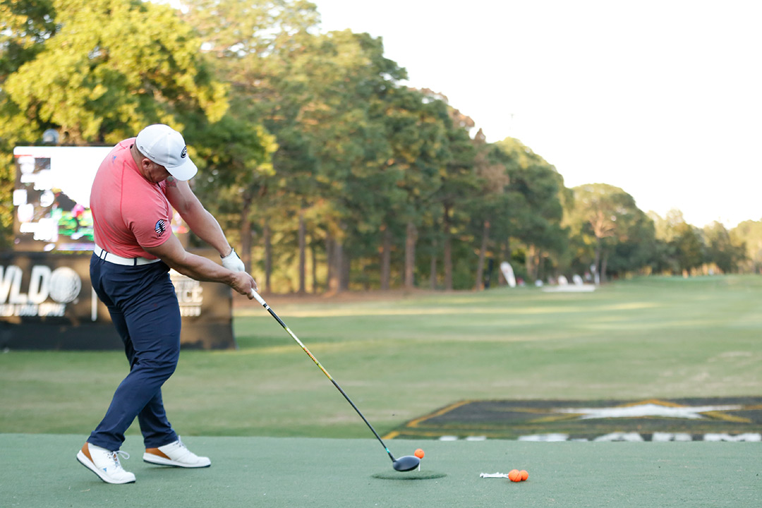 Golfer drives golfball from a tee.