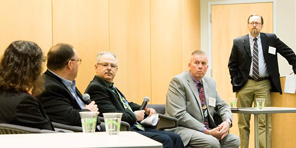 panel speakers in chairs next to a podium