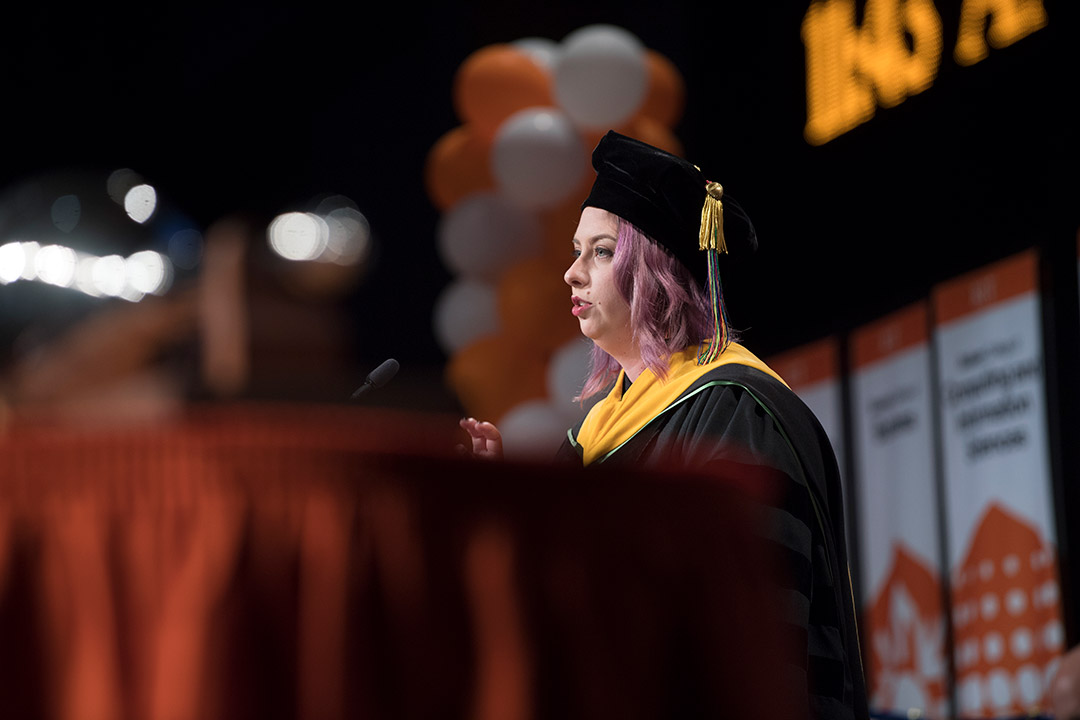 Faculty member in regalia speaks at podium.