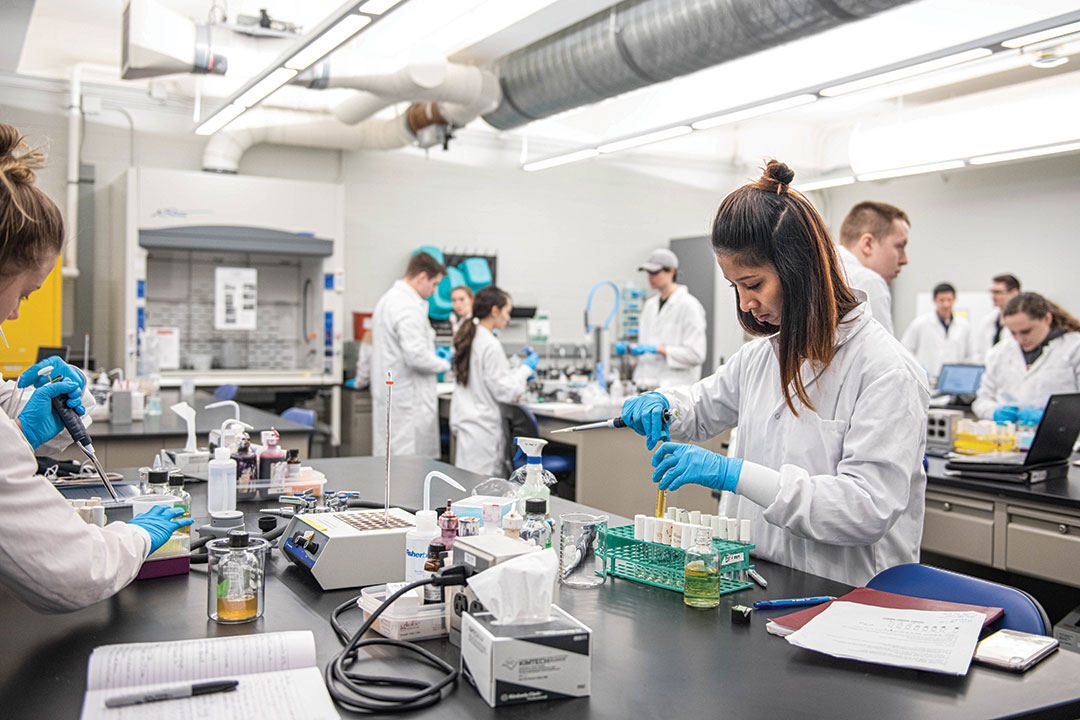 Student in lab coat works with pipette.