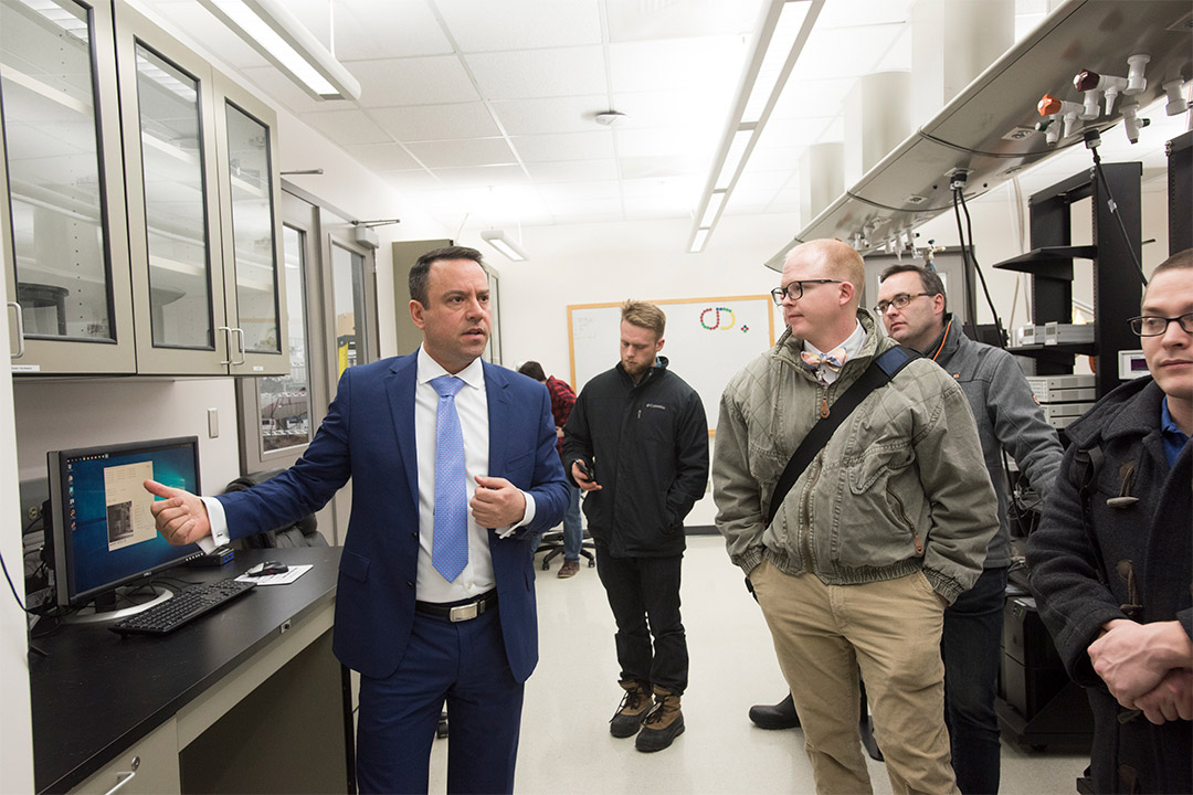 Man in suit leads tour of lab facility.