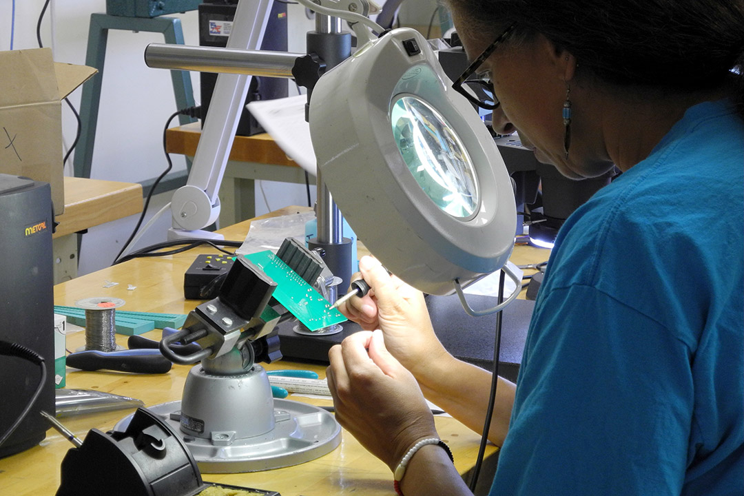 Woman looks like circuit board through magnifying lens.