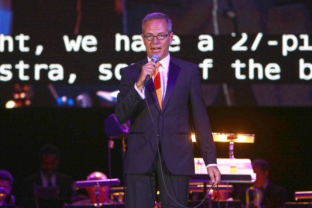 Man speaks with microphone on stage.