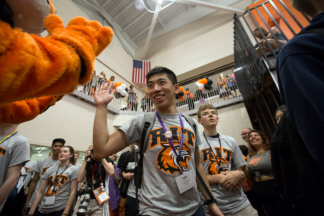 New student high-fives Tiger mascot.