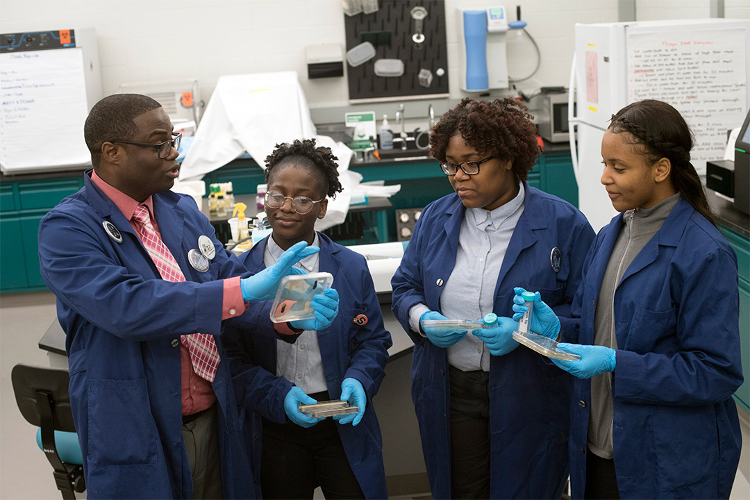 Professor and three students look at bacteria samples.