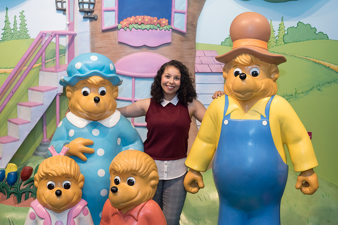 Student stands with life-like statues of the Berenstain Bears.