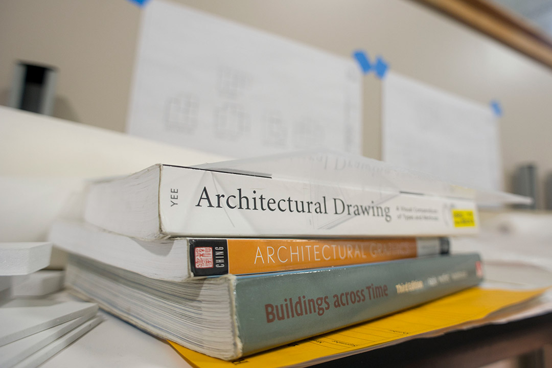 Three architecture books stacked on top of each other on table.