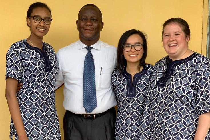 Students wearing traditional Nigerian dress stand with professor.