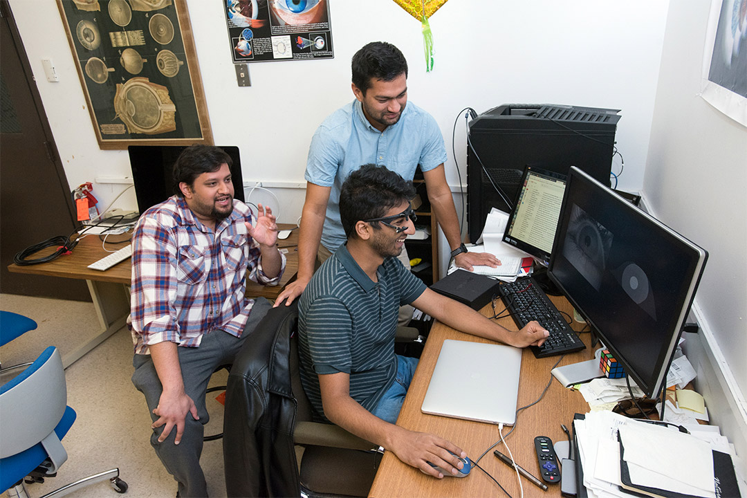 Three researchers look at eye-tracking software on computer.