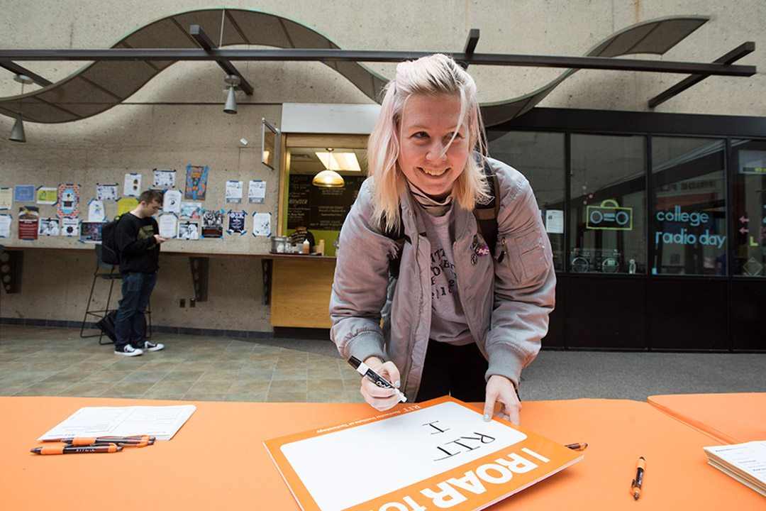 Student writes on dry-erase board during ROAR Day.