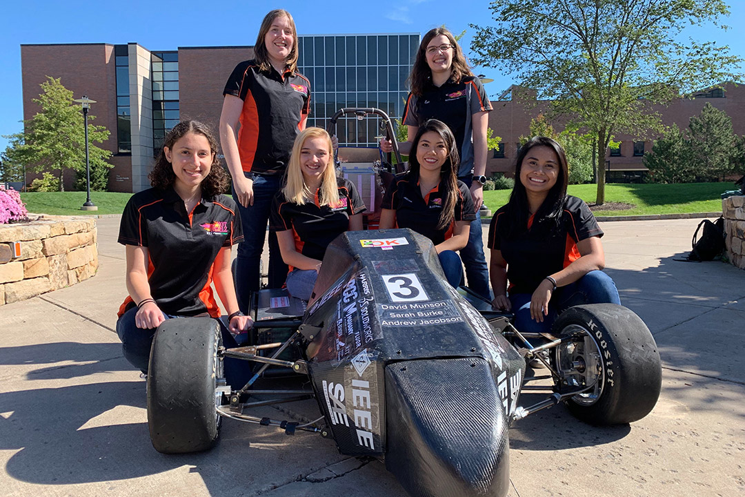 Six members of racing team pose with Formula car.