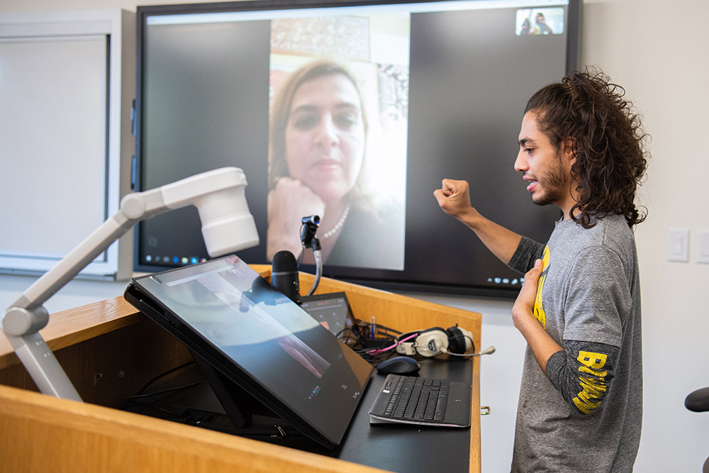 Student speaks with woman in Italy though videoconferencing equipment.