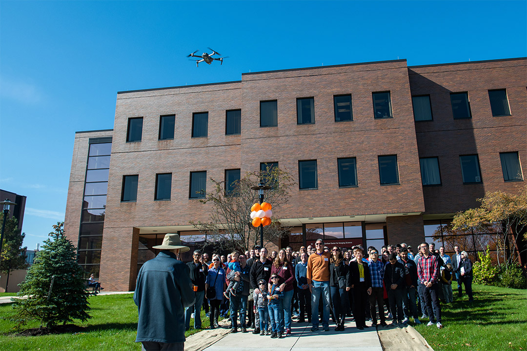 group of people stands in front of brick building for photo.