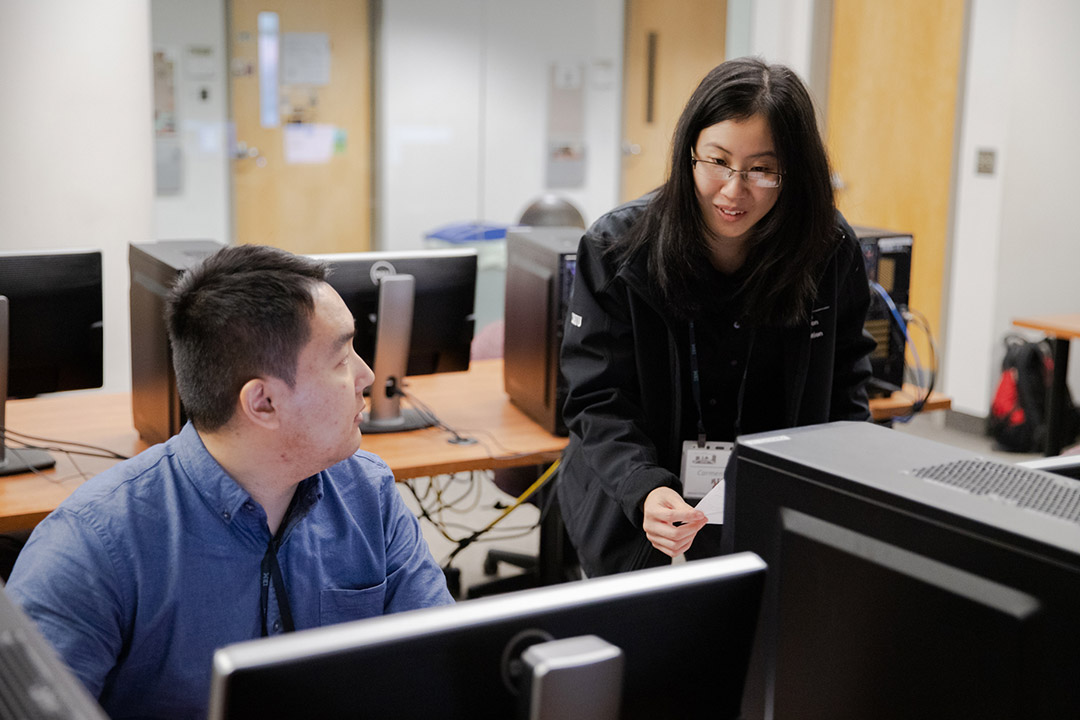 Two students work on computer.