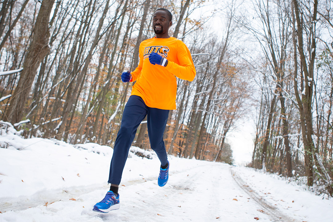 Student jogging outside on snowy path.