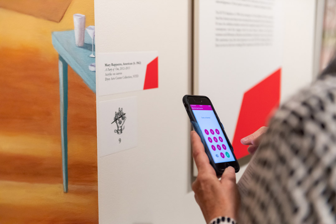 Person using app on smartphone to scan number next to piece of art.