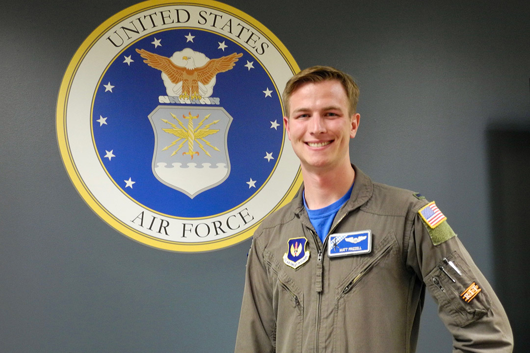 U.S. Air Force member stands in front of Air Force seal.