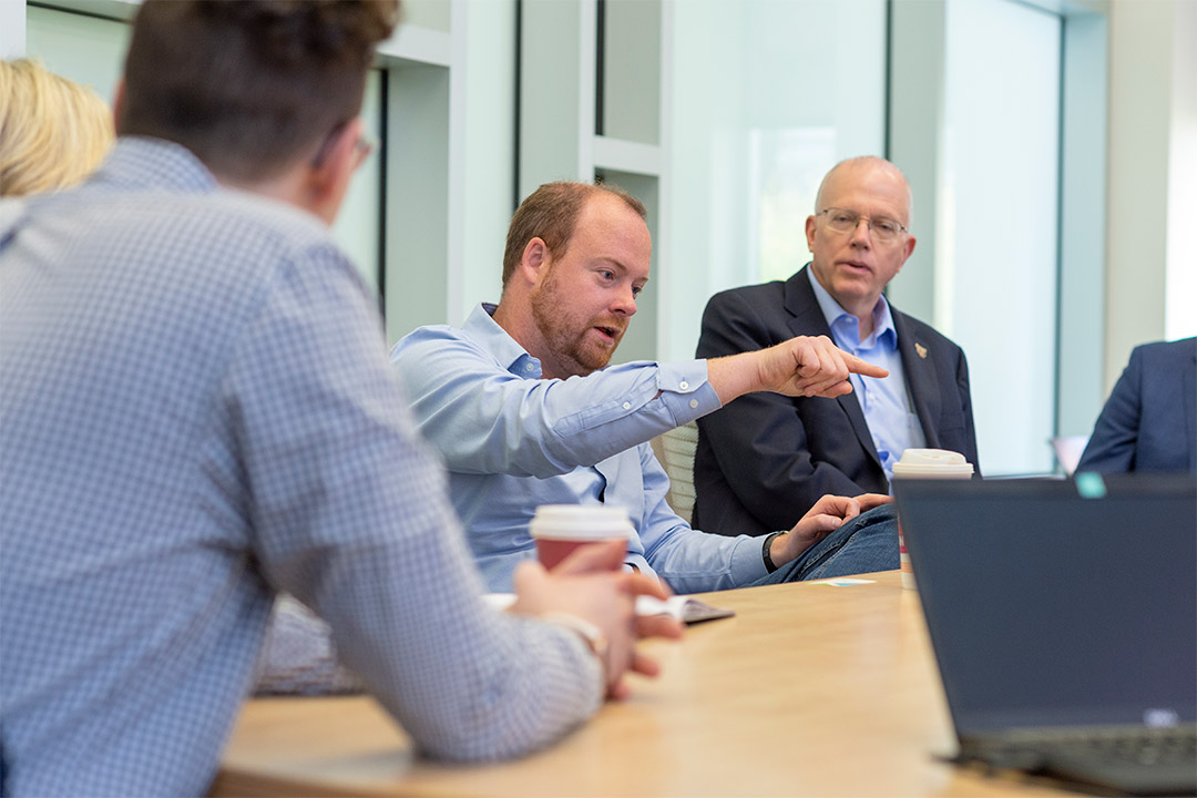 Alumnus and President David Munson talk at table with others.