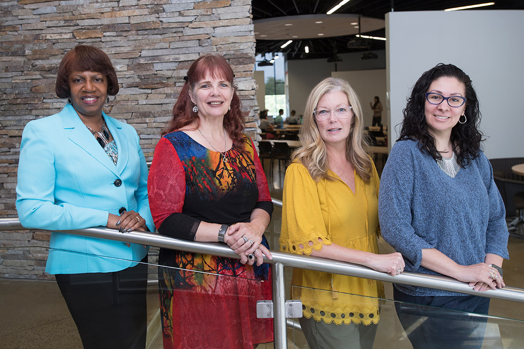 Four faculty/staff members stand in a row.