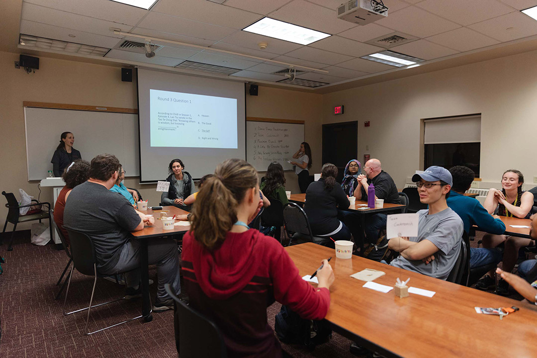 Students sit at tables in classroom.