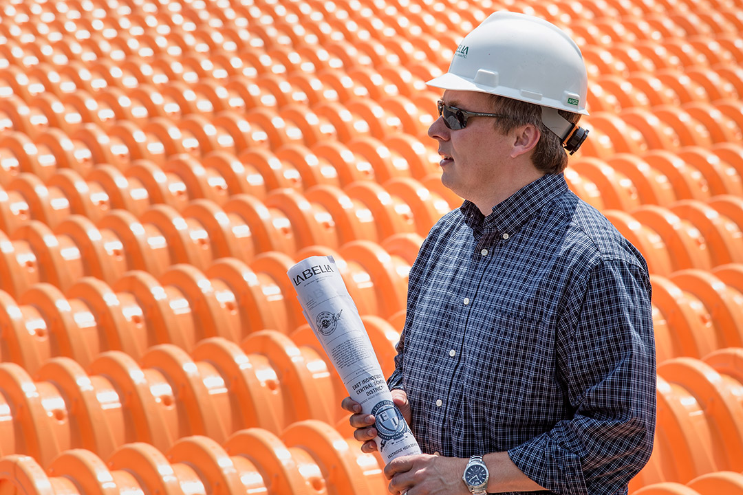 Man wearing hard hat holding blueprints.