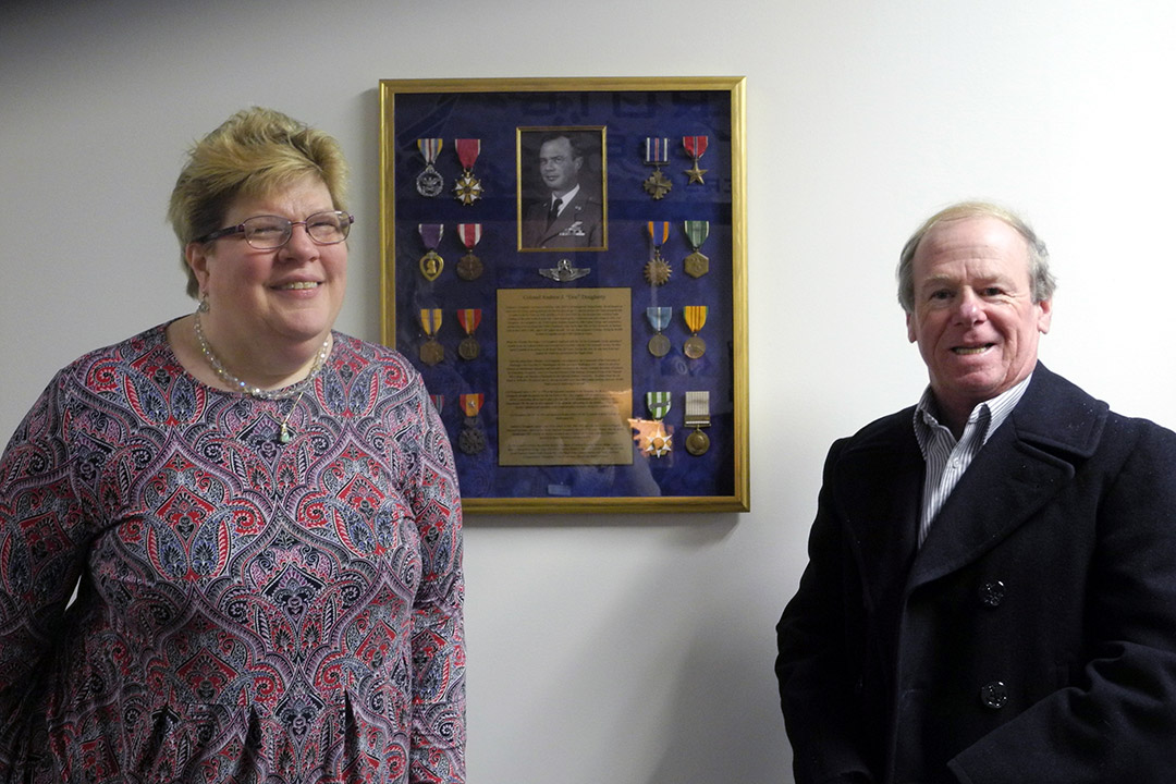 man and woman standing next to display of military medals.