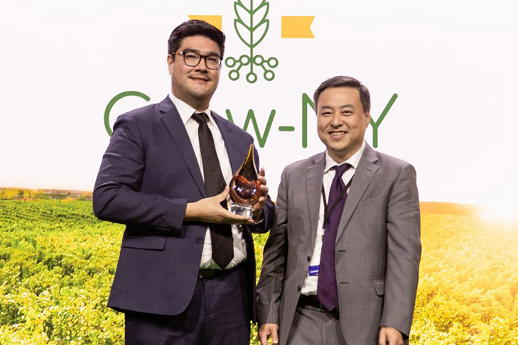 Two businessmen stand holding award.