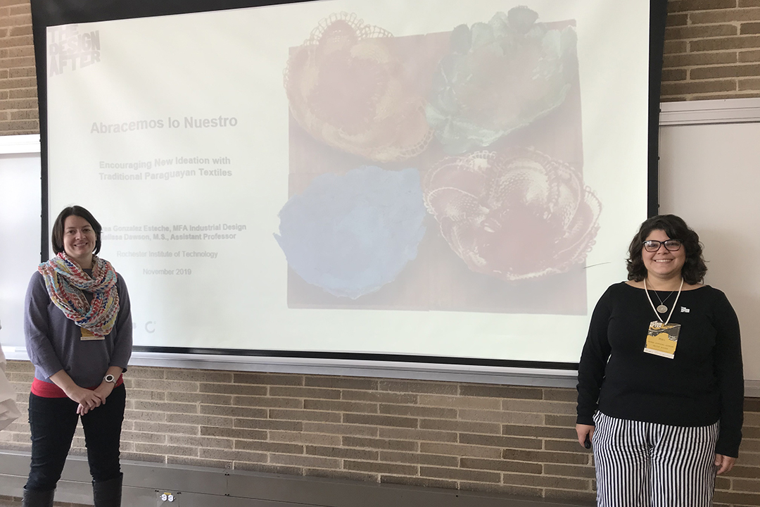 Melissa Dawson and Andrea Gonzalez Estache stand alongside a projected slide of their presentation in Colombia.