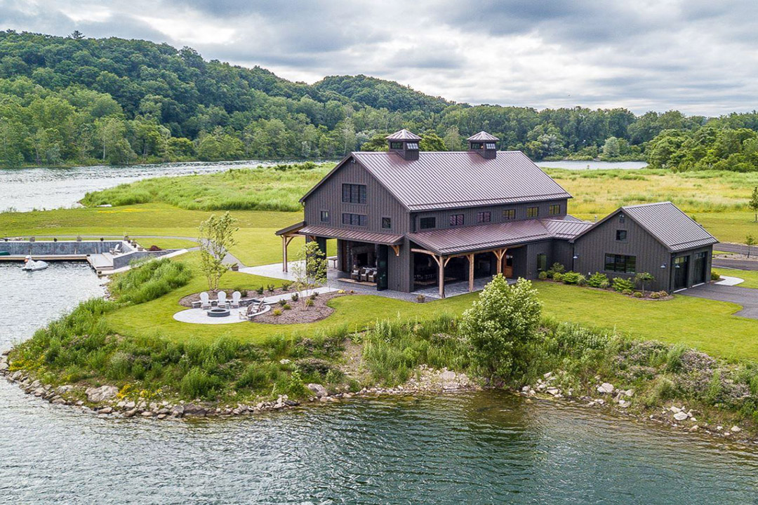 exterior shot of home on large property surrounded by trees and water.