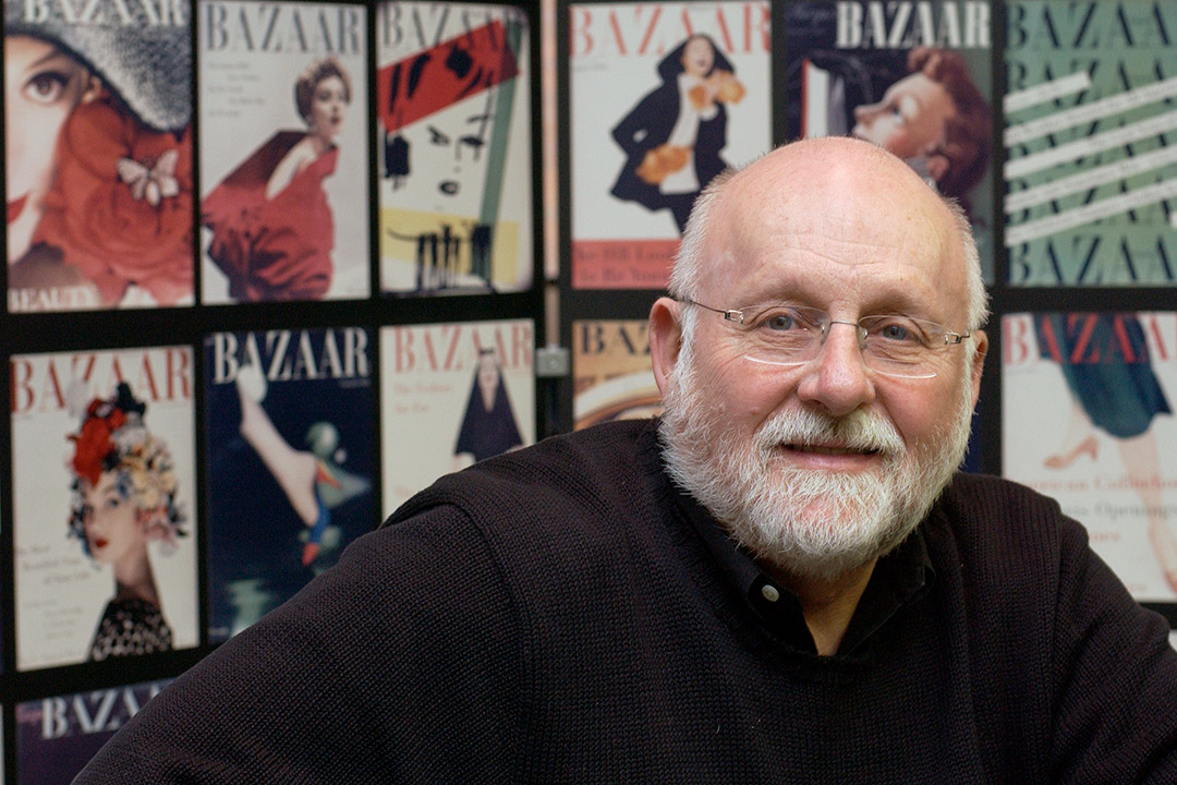 R. Roger Remington with Harper's Bazaar magazines in the background.