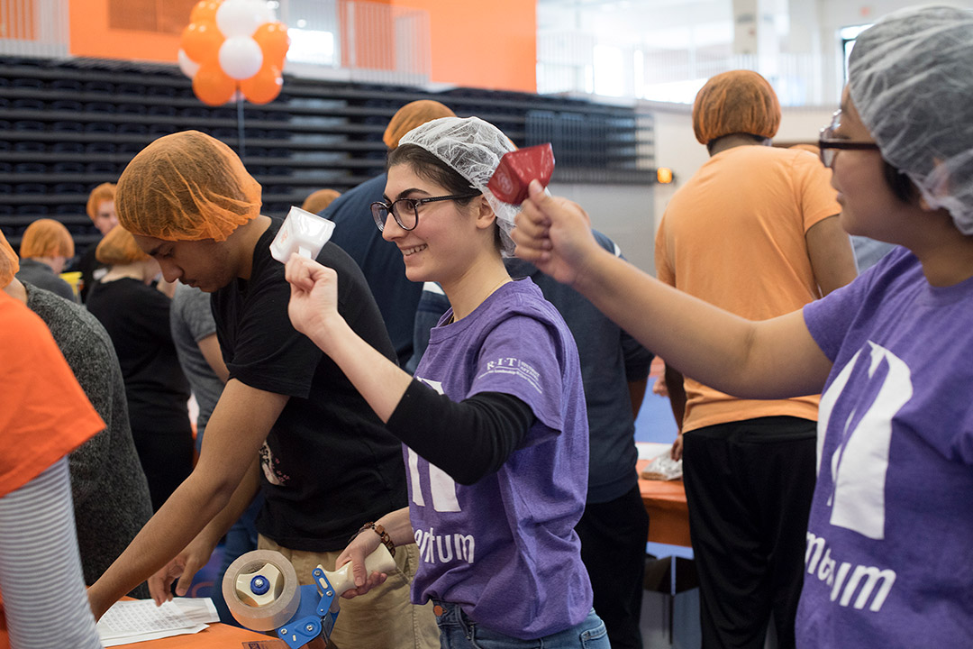 two students in assembly line ringing cowbells.