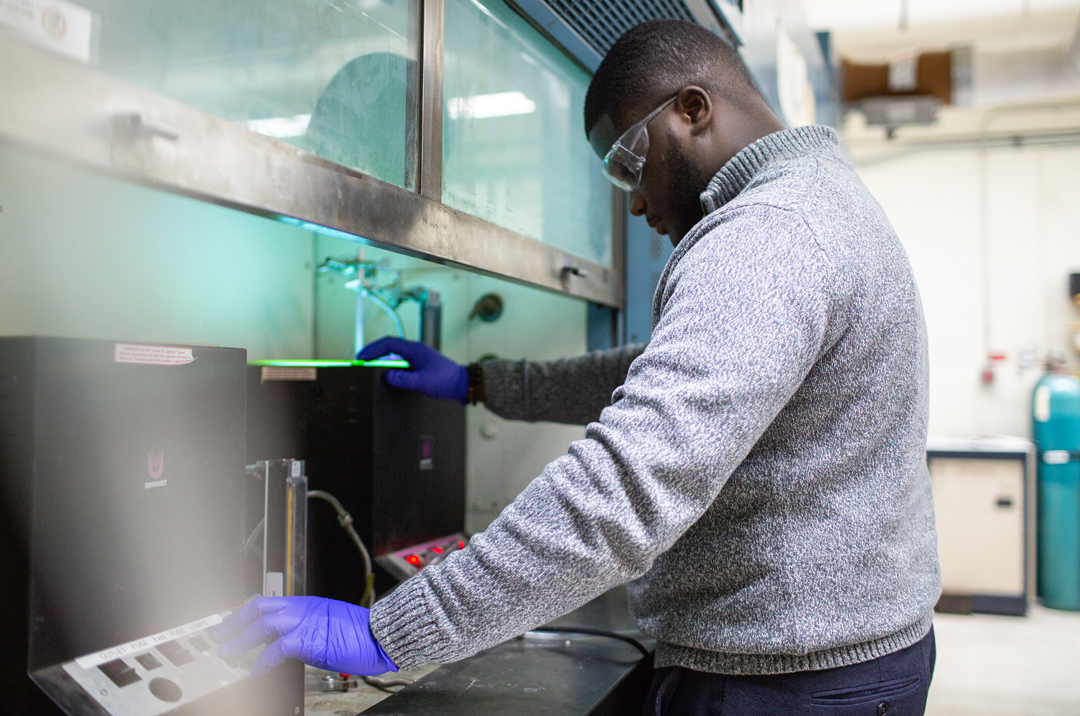 male student working on equipment in chemistry lab