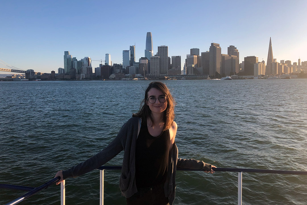 student poses with San Francisco skyline in background.