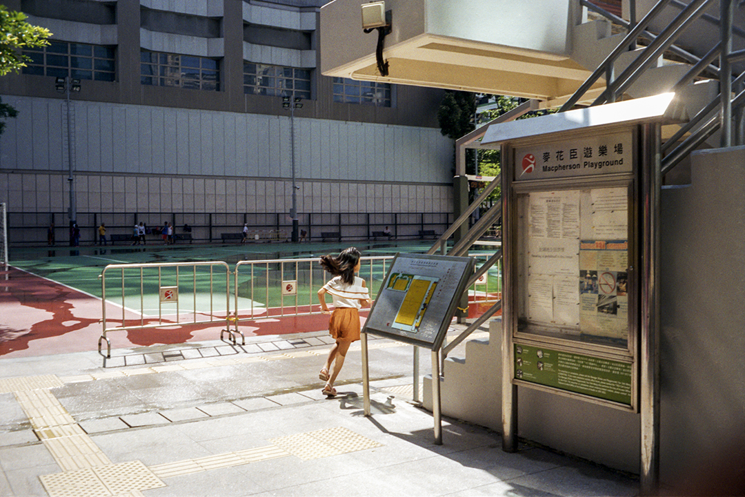 A young girl runs around the corner of a building. 