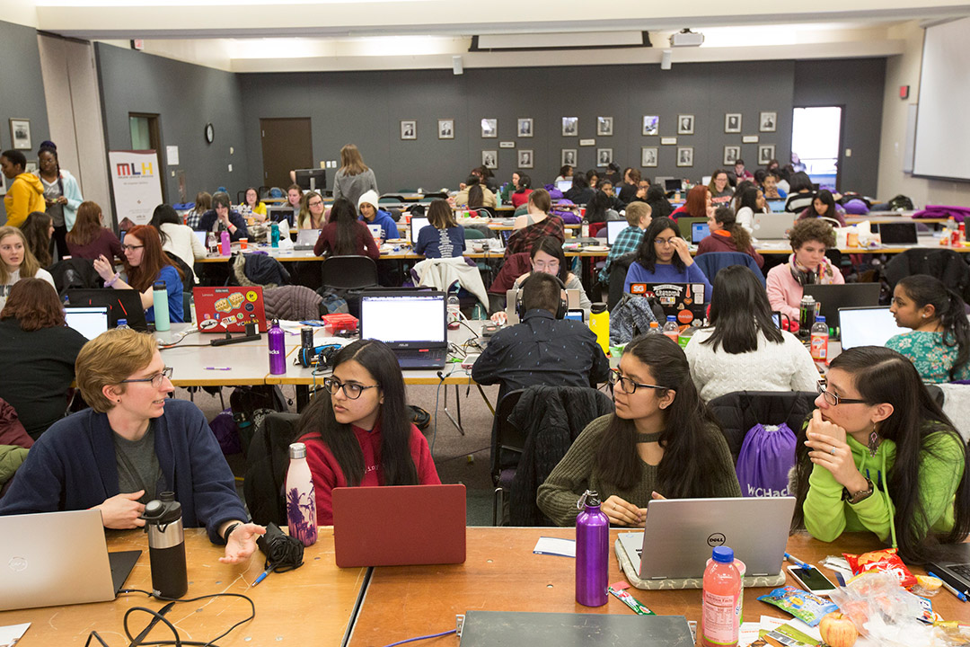 classroom of students sitting at tables with laptops.