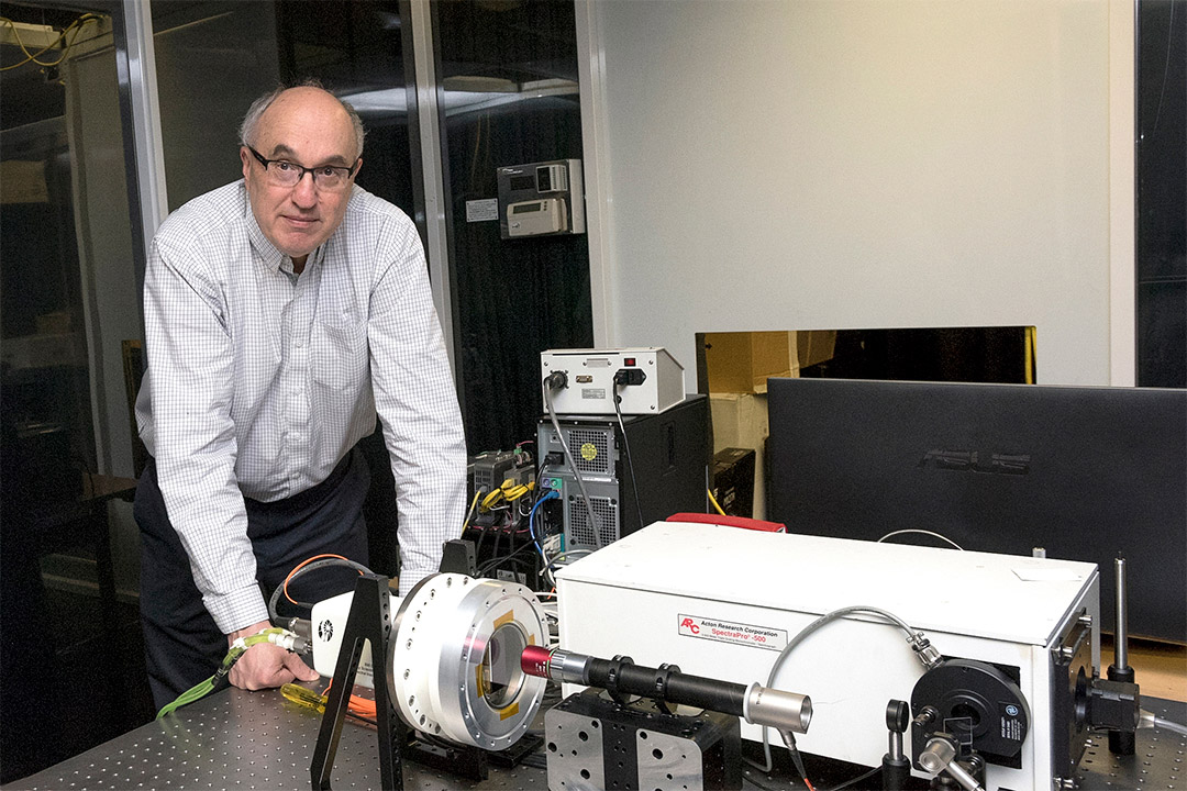 professor standing at table with imaging instrument.