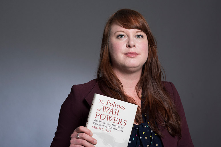 professor holding book titled: The Politics of War Powers.