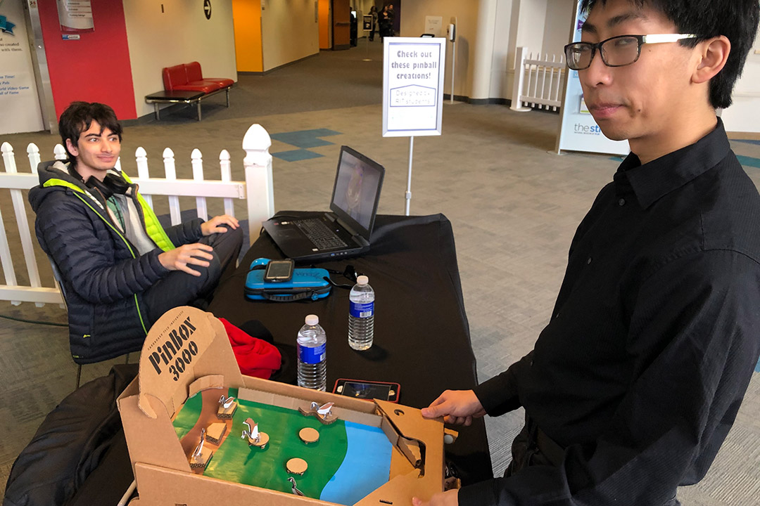 student playing cardboard prototype of a pinball machine.