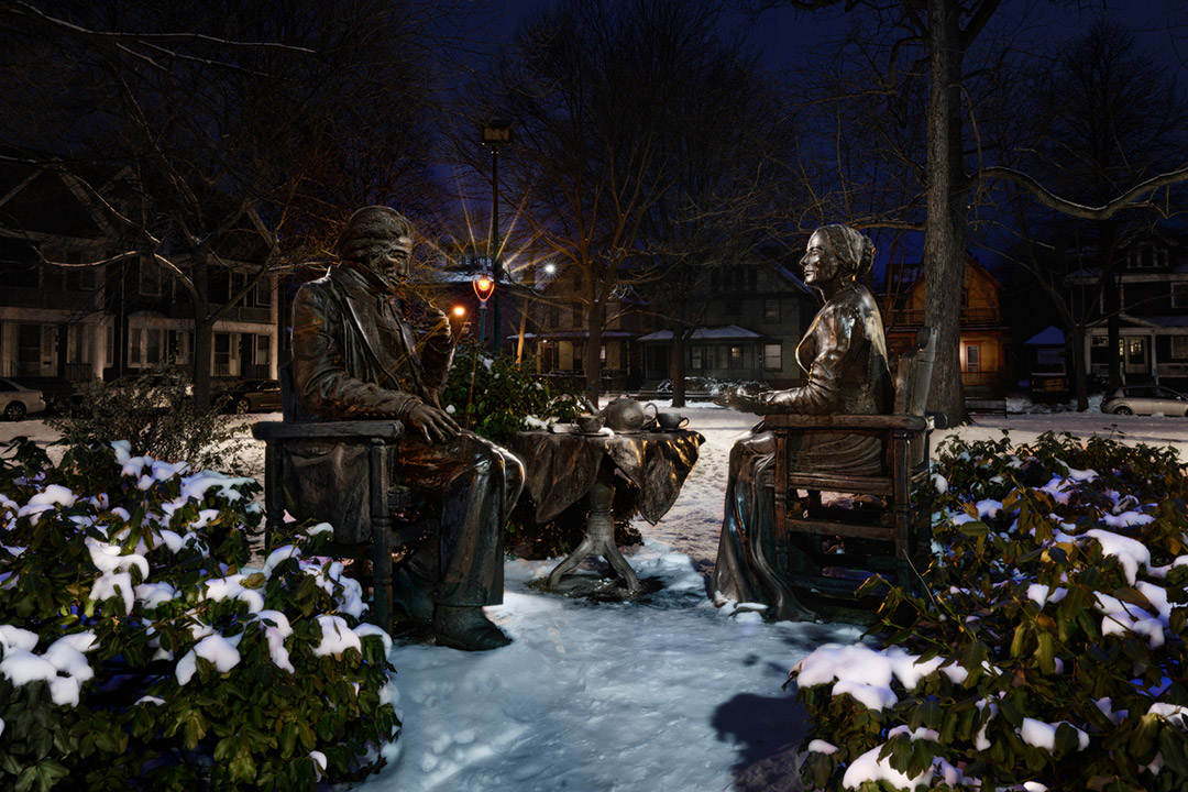 nighttime shot of statues of Susan B. Anthony and Frederick Douglass.