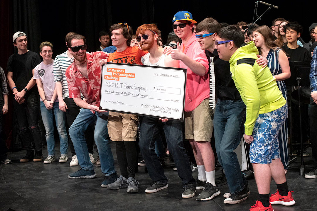 students standing on stage with giant check.