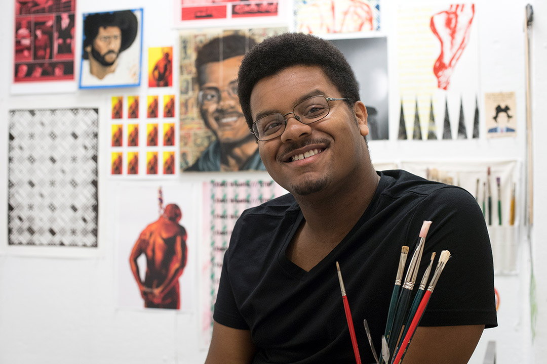 student posing with art work in the background.