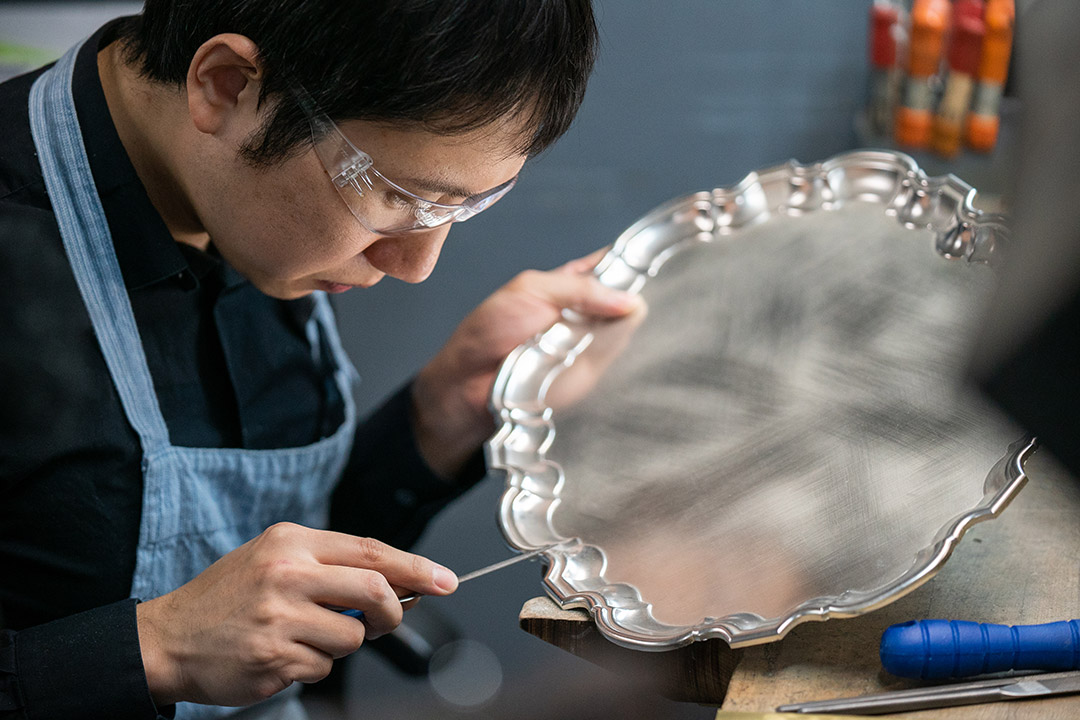 Kibaek Sung metalsmithing a silver platter.