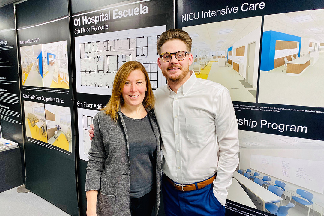 two people standing in front of hospital design posters.