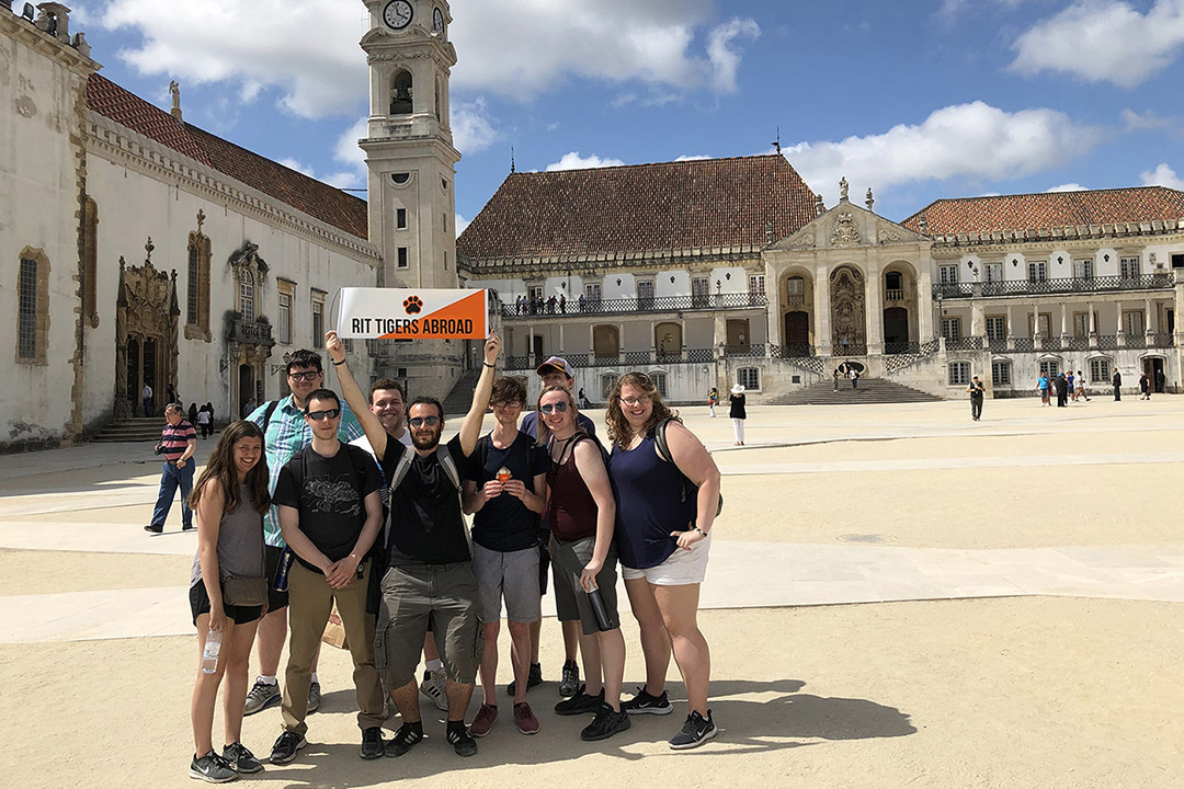 group of students holding "RIT Tigers Abroad" banner in square in Portugal.