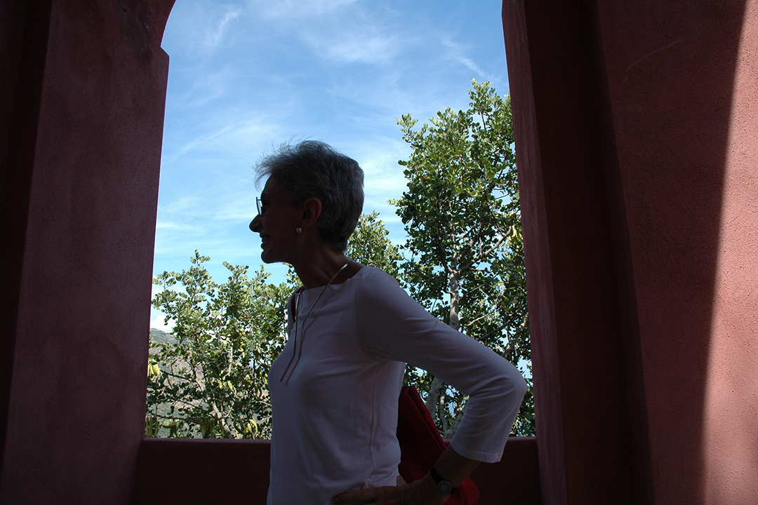 Lella Vignelli stands near a window with a blue sky in the background.