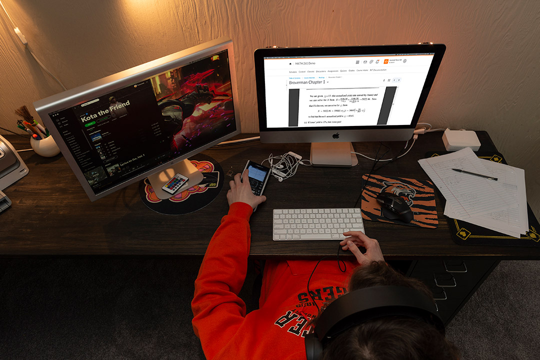 overhead view of student sitting a desk with two computer monitors.