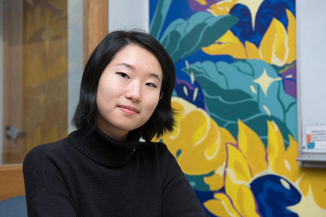 student posing with sunflower-inspired mural artwork.