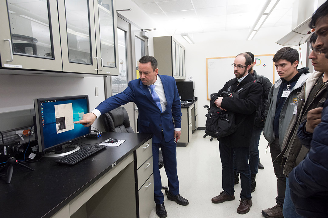 researcher giving demonstration of computer equipment to visitors.